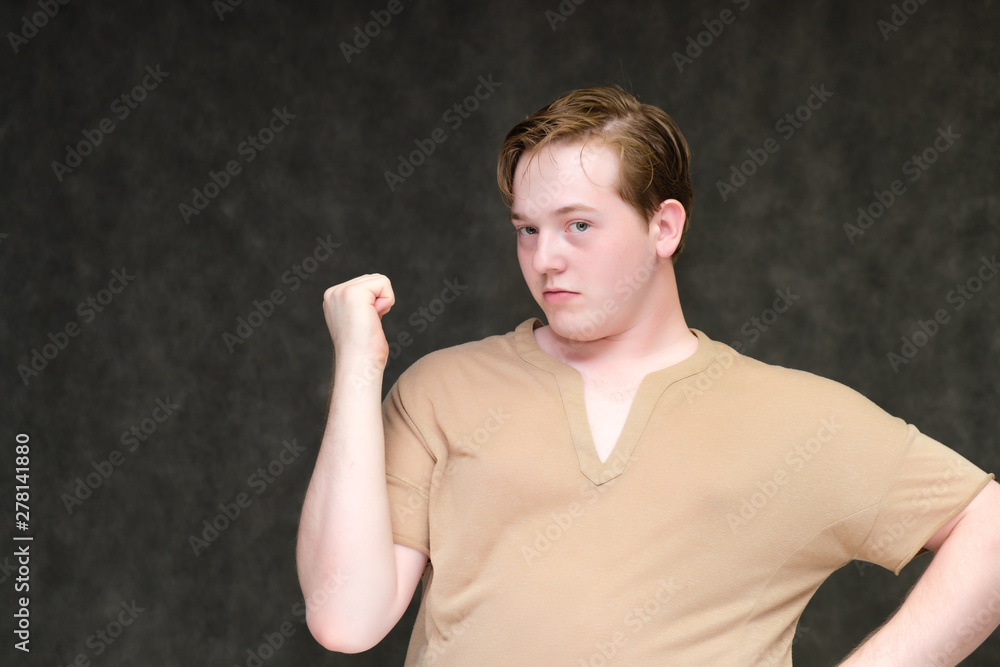 Portrait to the waist on a gray background of a handsome young man in a brown T-shirt. stands directly in front of the camera in various poses, talking, demonstrating emotions. Portrait to the waist on a gray background of a handsome young man in a brown T-shirt. stands directly in front of the camera in various poses, talking, demonstrating emotions.