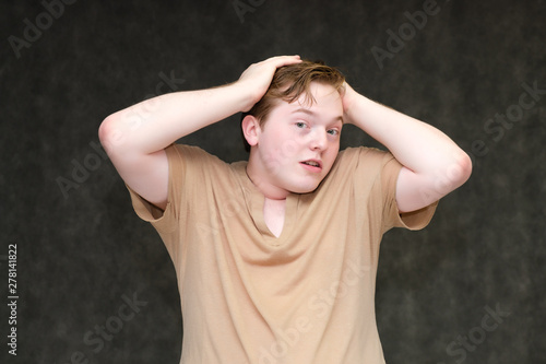 Portrait to the waist on a gray background of a handsome young man in a brown T-shirt. stands directly in front of the camera in various poses, talking, demonstrating emotions.