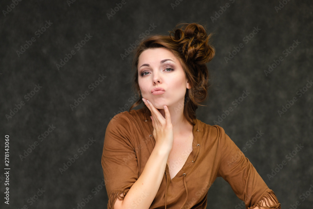Portrait below breast over gray background of pretty young brunette woman in brown dress with beautiful hair. Standing in different poses, talking, showing with hands, demonstrating emotions. Portrait below breast over gray background of pretty young brunette woman in brown dress with beautiful hair. Standing in different poses, talking, showing with hands, demonstrating emotions.