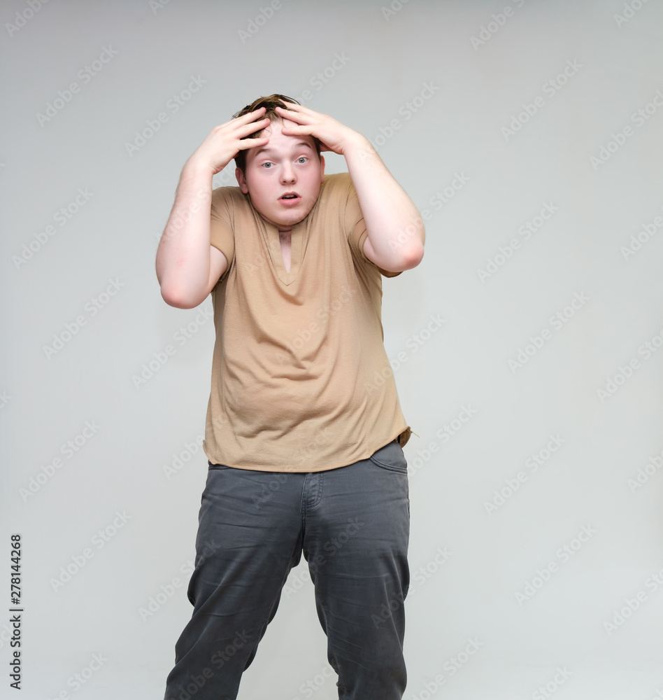 Portrait of a knee on a white background cute young man in a brown T-shirt in jeans. Standing right in front of the camera in various poses, talking, demonstrating emotions. Portrait of a knee on a white background cute young man in a brown T-shirt in jeans. Standing right in front of the camera in various poses, talking, demonstrating emotions.
