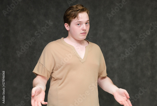 Portrait to the waist on a gray background of a handsome young man in a brown T-shirt. stands directly in front of the camera in various poses, talking, demonstrating emotions.