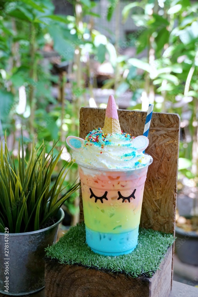 Selective focus of iced milk tea topping with whipping cream in takeaway glass on grass table in café restaurant, Summer drink, ready to eat, relaxed time, Vertical Selective focus of iced milk tea topping with whipping cream in takeaway glass on grass table in café restaurant, Summer drink, ready to eat, relaxed time, Vertical