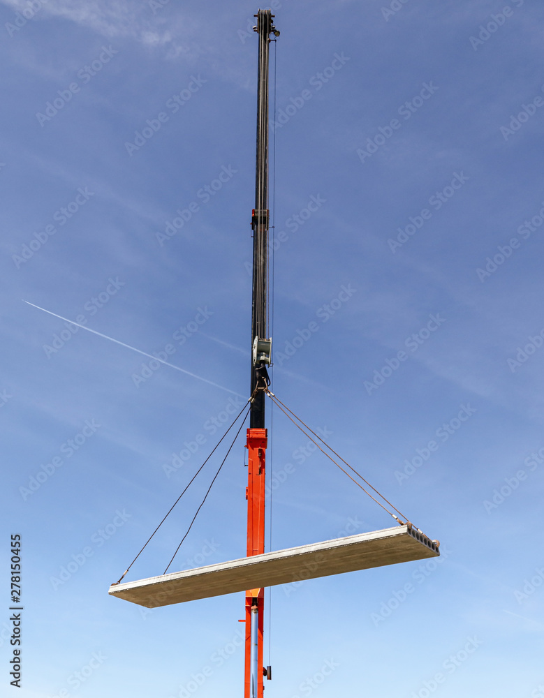 A crane raised a concrete slab at a construction site at home A crane raised a concrete slab at a construction site at home