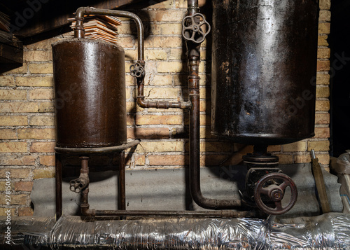 Rusty boiler room pipes. Old metal boiler generating heating and delivering it to home through pipeline. Hot water or gas is being delivered with this system
