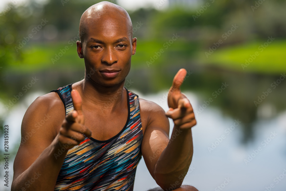 Naklejka premium Athletic man pointing fingers at the camera. Image lit with off camera flash and natural lighting