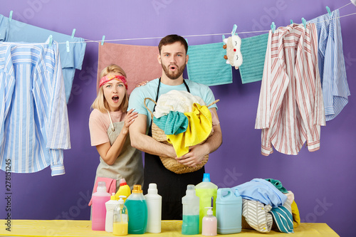 Shocked emotional couple having much work to do being in panic. isolated blue background, studio shot. emotiona and feeling.clean clothes hanging on the clothesline