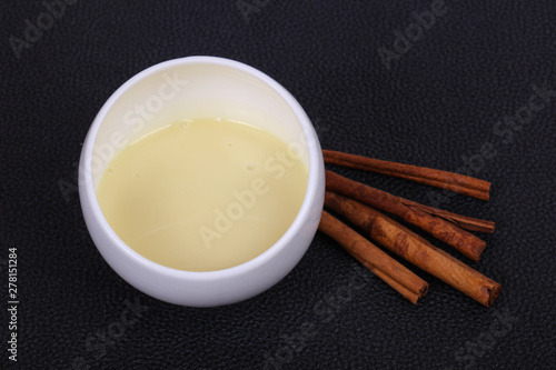 Condenced milk in the bowl with sinnamon and pastry photo