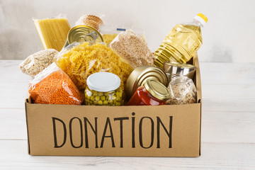 Open cardboard box with oil, canned food, cereals and pasta.