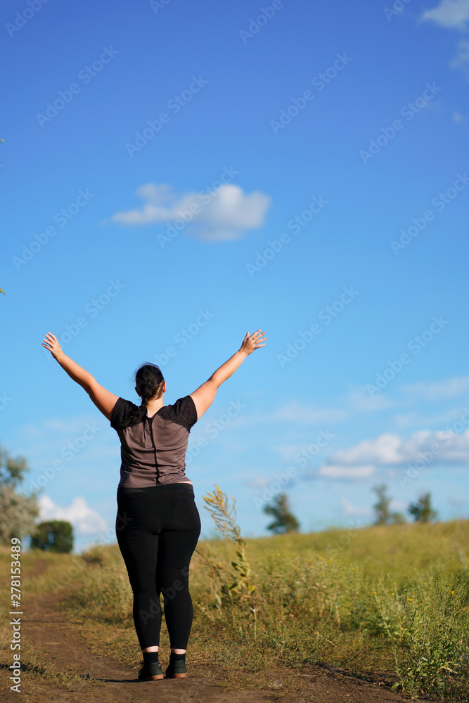 Body positive, success, freedom, happiness, confidence, self esteem. Overweight woman rising hands to the sky. Obesity and outdoor activity Body positive, success, freedom, happiness, confidence, self esteem. Overweight woman rising hands to the sky. Obesity and outdoor activity