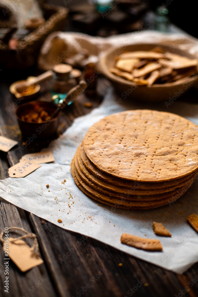 Homemade stack of baked layers of Russian traditional honey cake on baking paper on wooden rustic table Homemade stack of baked layers of Russian traditional honey cake on baking paper on wooden rustic table