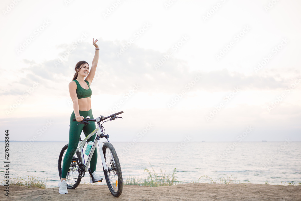 Beautiful young brunette woman resting after bicycle ride at sunrise. Model listening to music with wireless earbuds in the morning. Beautiful young brunette woman resting after bicycle ride at sunrise. Model listening to music with wireless earbuds in the morning.