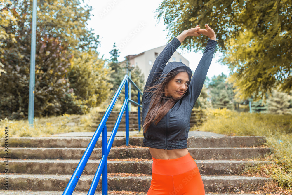 Healthy sports lifestyle. Athletic young woman in sports dress doing  fitness exercise. Portrait of beautiful young woman exercising in the park.  Fitness woman doing warm up exercises outdoors Stock Photo