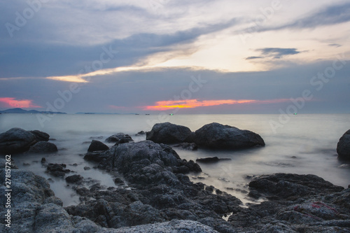 The shore of the calm sea of the Gulf of Thailand without people, waves shot on a long exposure. Large rocks in the foreground 