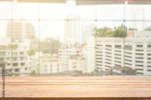 Blur background of white window glass and city view with empty of wood table.