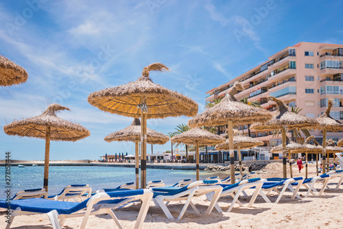 Beach chairs and umbrellas in front of a hotel on a paradisiacal beach.