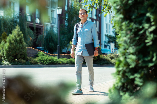 Man wearing smart watch walking to office with laptop in hands © Viacheslav Yakobchuk