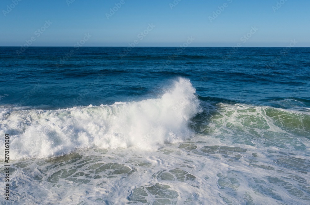 Blue ocean waves crash on a tetrapods breakwater forming white foam. Blue ocean waves crash on a tetrapods breakwater forming white foam.