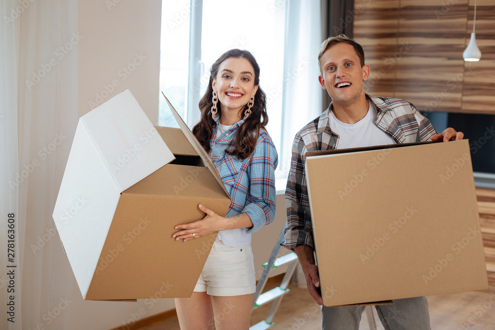 Couple holding boxes with things while moving to new house Couple holding boxes with things while moving to new house