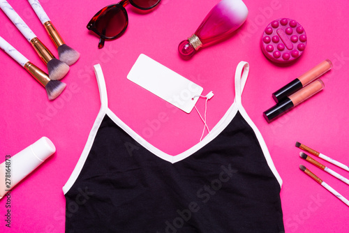Black bodysuit, skin tight garment and cosmetics on pink backgroudn, flat lay top view