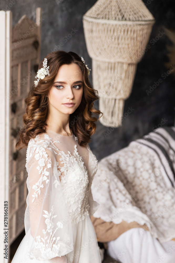 Fototapeta premium Portrait romantic bride looking away. Bride with makeup and hairstyle in a luxury wedding dress. Elegant hair accessorie. Studio boho indoor photo. Сlose-up.