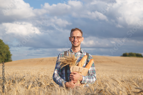 Wide smiling farmer or baker with baguettes in rye, wheat field © vladdeep