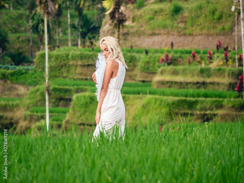 Blondie girl in straw hat and white dress on the rice fields