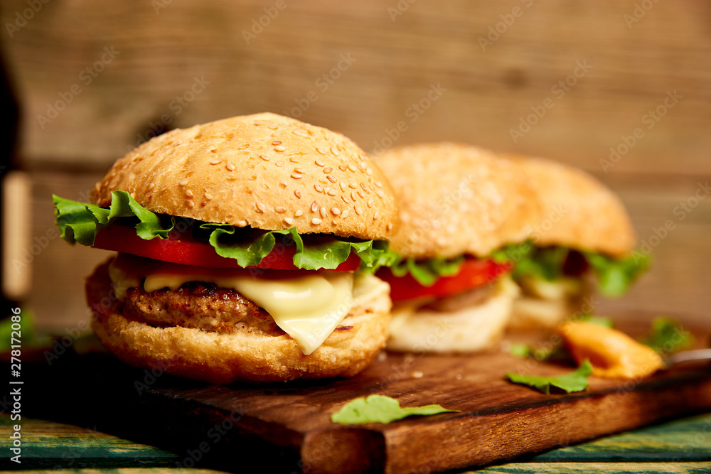 Craft beef burger on wooden table isolated on black background..Street food, fast food. Homemade juicy burgers with cheese and on the wooden table. Copy space. Craft beef burger on wooden table isolated on black background..Street food, fast food. Homemade juicy burgers with cheese and on the wooden table. Copy space.