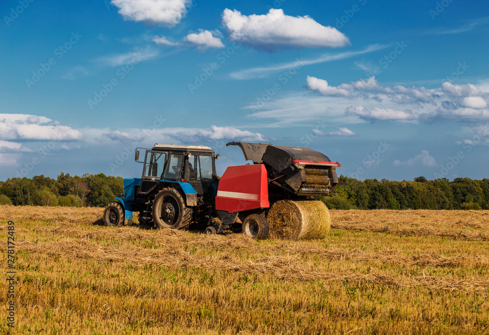 Obraz premium Straw harvesting with the help of a rotary roll forming machine in the unit with a tractor