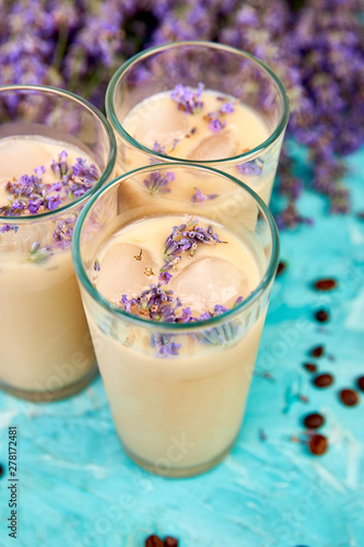 Summer drink iced coffee with lavender in glass and coffee beans on blue background. Good Morning concept. Baeutiful ice coffee.