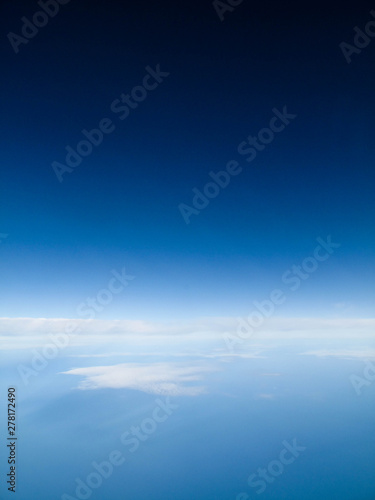 Clear blue sky with calming bed of white clouds from a flight in Spring or Summer