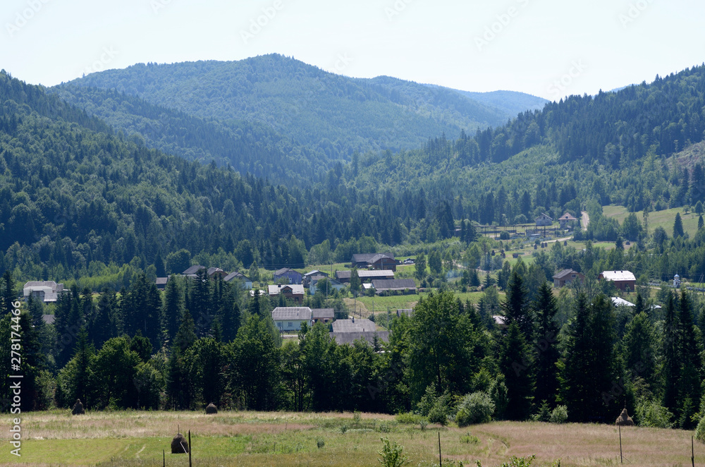 View of the Carpathian village: country houses, forest and mountains..Lugi village, Ukraine