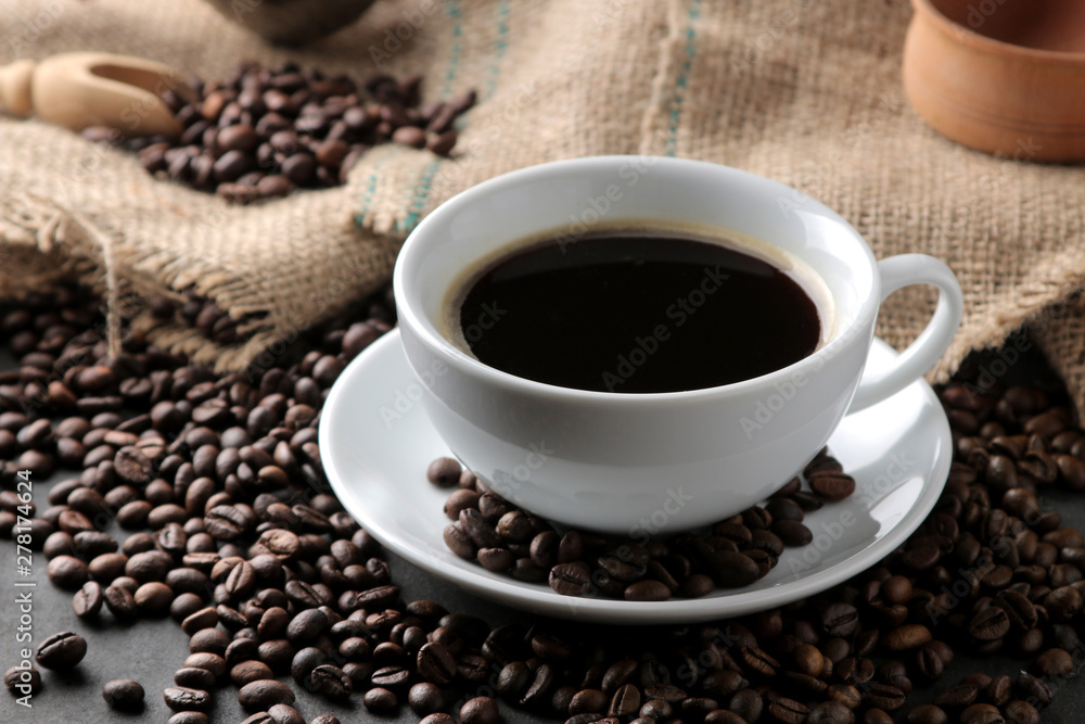 Roasted coffee grains and a cup of coffee on a brown wooden background. Robusta, Arabica. Roasted coffee grains and a cup of coffee on a brown wooden background. Robusta, Arabica.