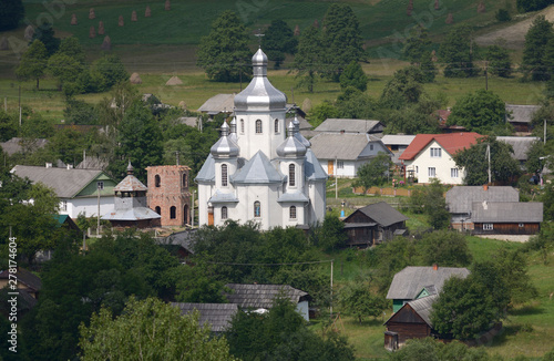 View of the Carpathian village  catholic church  country houses  gardens and mountains. Lugi village  Ukraine