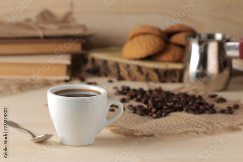 Coffee in a white cup and roasted coffee grains on a natural wooden table. Robusta, Arabica