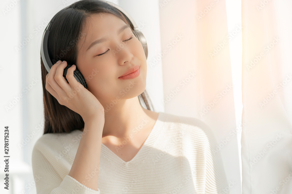 relex and peaceful asian woman enjoy weekend with music headphone morning sunlight near window home background relex and peaceful asian woman enjoy weekend with music headphone morning sunlight near window home background