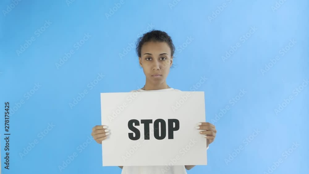 Afro-American Girl Activist With Stop Poster on blue background Afro-American Girl Activist With Stop Poster on blue background