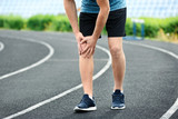 Man in sportswear suffering from knee pain at stadium, closeup