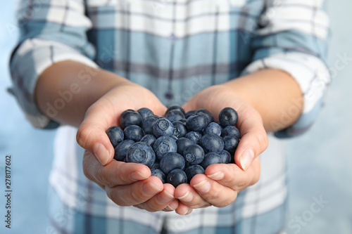 Young woman holding tasty ripe blueberries, closeup