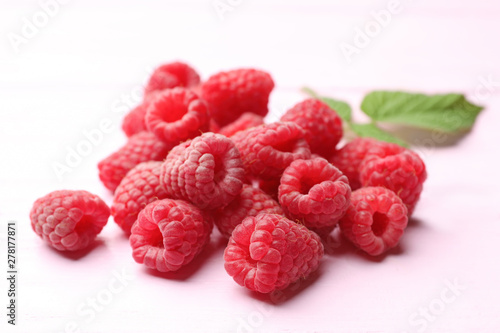 Delicious fresh ripe raspberries on pink wooden table, closeup view