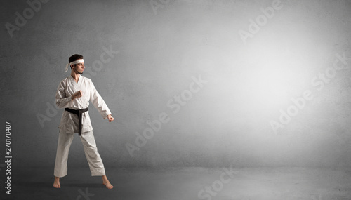 Small karate man fighting in an empty grey copy space