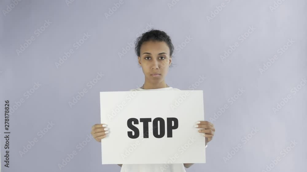 Afro-American Girl Activist With Stop Poster on grey background Afro-American Girl Activist With Stop Poster on grey background
