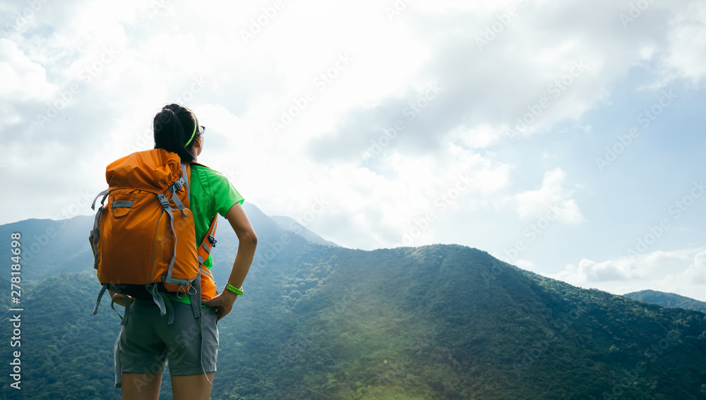 Successful woman backpacker enjoy the view on summer mountain peak