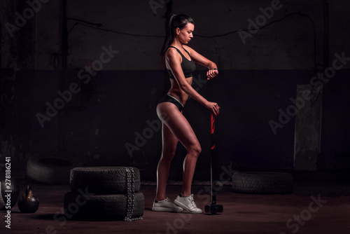 Fit young woman checking her smartwatch. Females resting after training session and looking at her wrist watch. Woman hold hammer