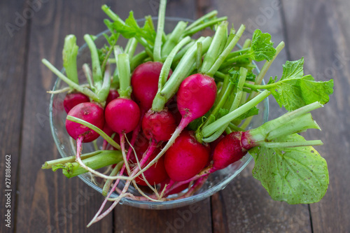 fresh radishes in a glass bowl on wooden table 