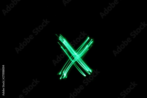 Long exposure photograph, light painting photography.  Letter x of an alphabet series, single letter, in neon green light, against a black background