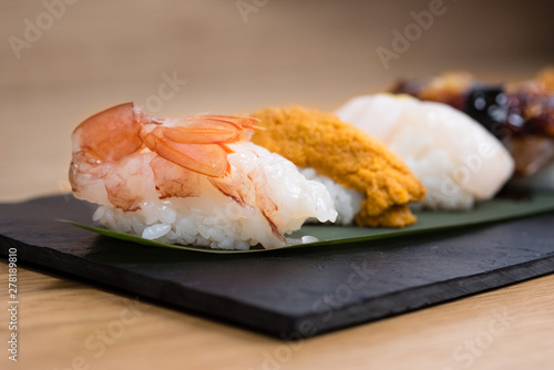 detail of steamed prawn nigiri, with background of nigiri with Pacific Sea Urchin, steamed salmon, steamed shrimp, caviar, roasted eel and squid