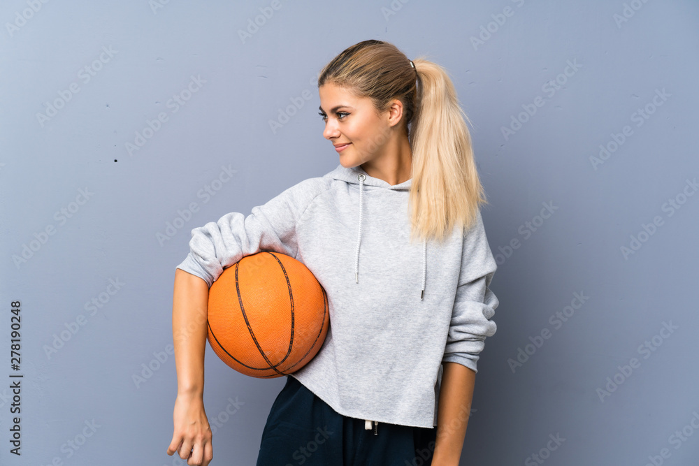 Teenager girl playing basketball over grey wall Teenager girl playing basketball over grey wall