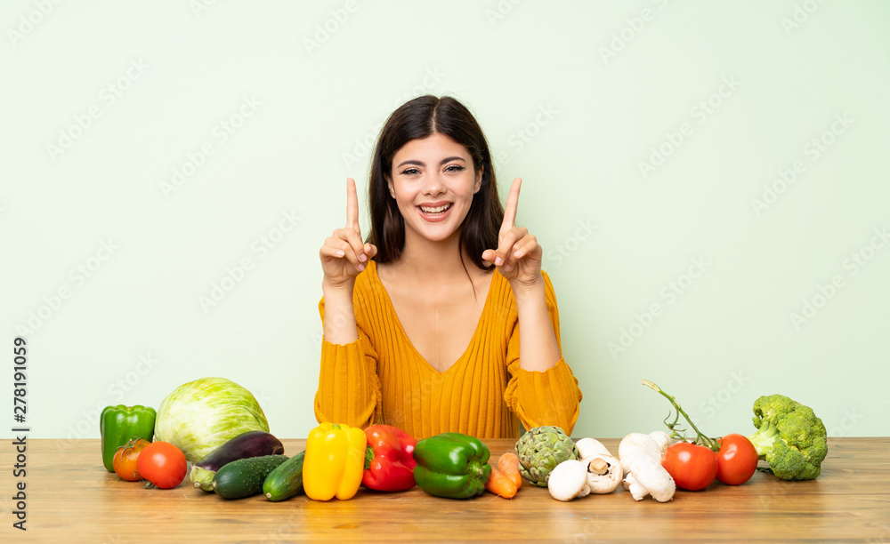 Teenager girl with many vegetables pointing up a great idea Teenager girl with many vegetables pointing up a great idea