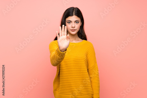 Teenager girl over isolated pink wall making stop gesture