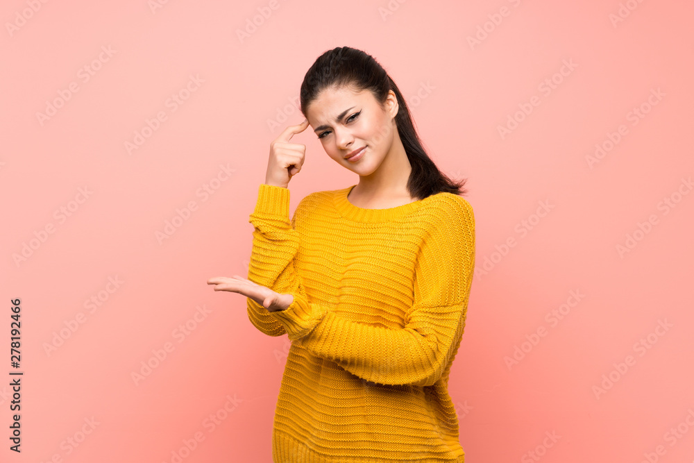 Teenager girl over isolated pink wall making the gesture of madness putting finger on the head Teenager girl over isolated pink wall making the gesture of madness putting finger on the head